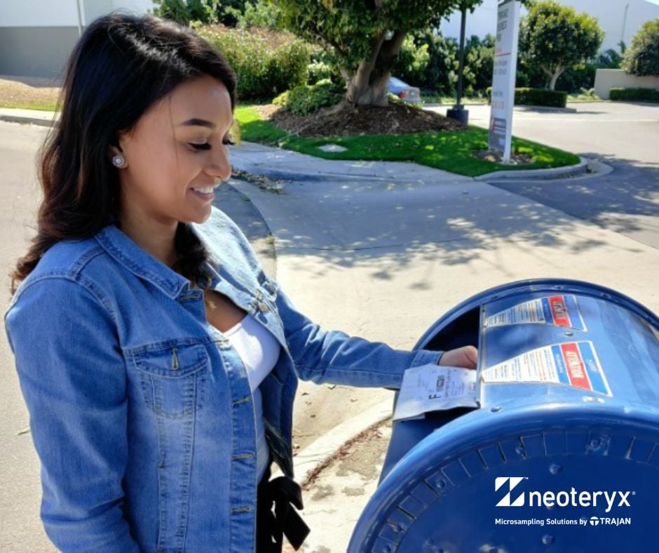 A young women drops off her dried blood microsamples into a standard mail box.