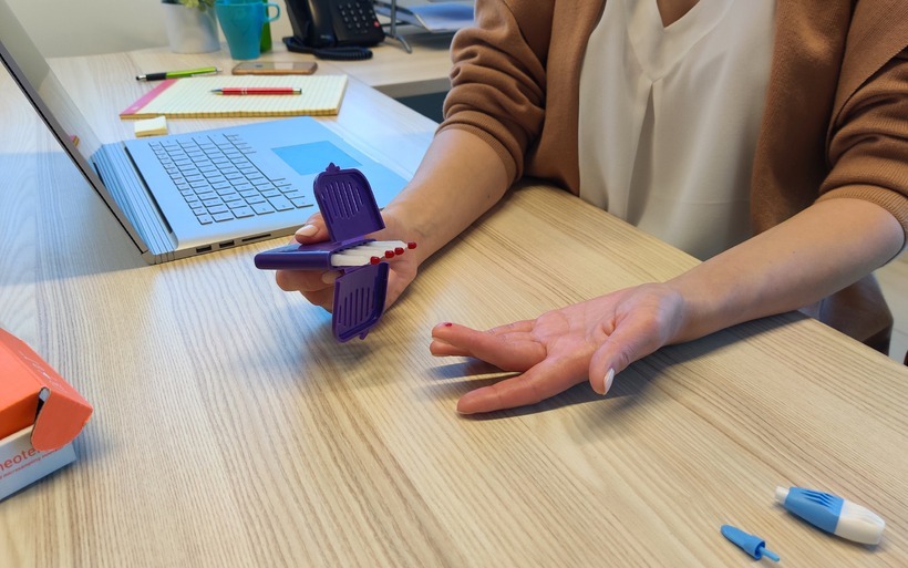 an office worker collects micro samples of blood via finger stick prick from the comfort of their office