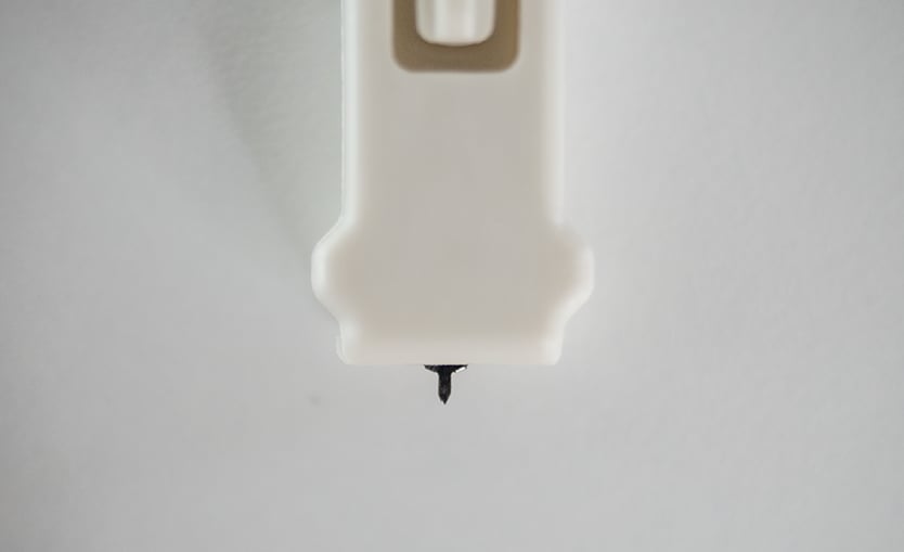 Close up photo of the Harpera device. the tiny collection tip.is seen protruding out from the device. 