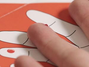 Nahaufnahme eines Fingers mit einem Bluttropfen, der sich nach dem Einstechen der Lanzette bildet