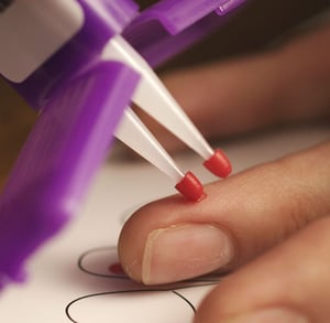 close up of a Mitra device collecting a drop of capillary blood from a finger