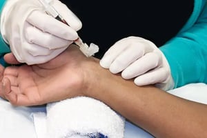 a lab technician takes an arterial blood sample in a clinical setting