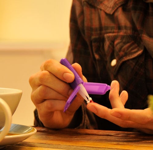 Entnahme eines Blutstropfens aus einem Finger im Heim des Patienten