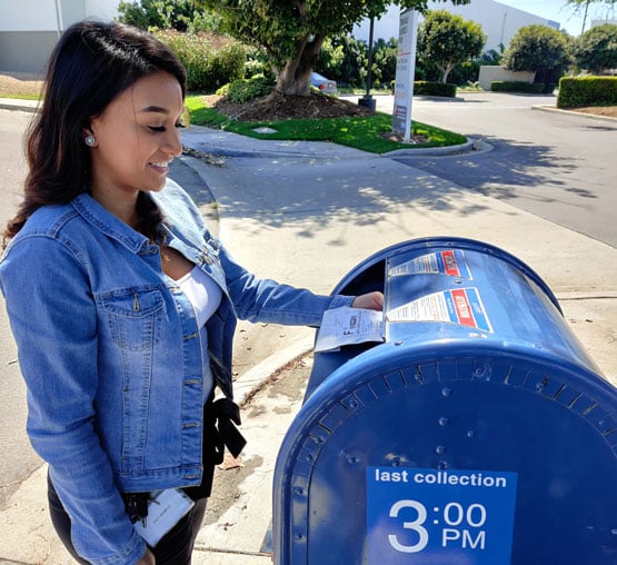 a young women puts a package of dried blood microsamples in a standard post office box
