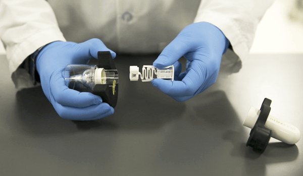 a pair of glved hands work with a hemapen QC device in a laboratory setting