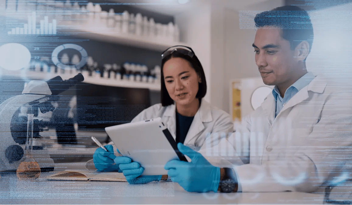 two scientist in lab coasts look at their findingx on a tablet in a laboratory setting