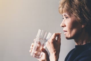 an elderly women is about to take a pill 