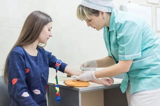 A nurse take a venipunture blood sample from a young girl