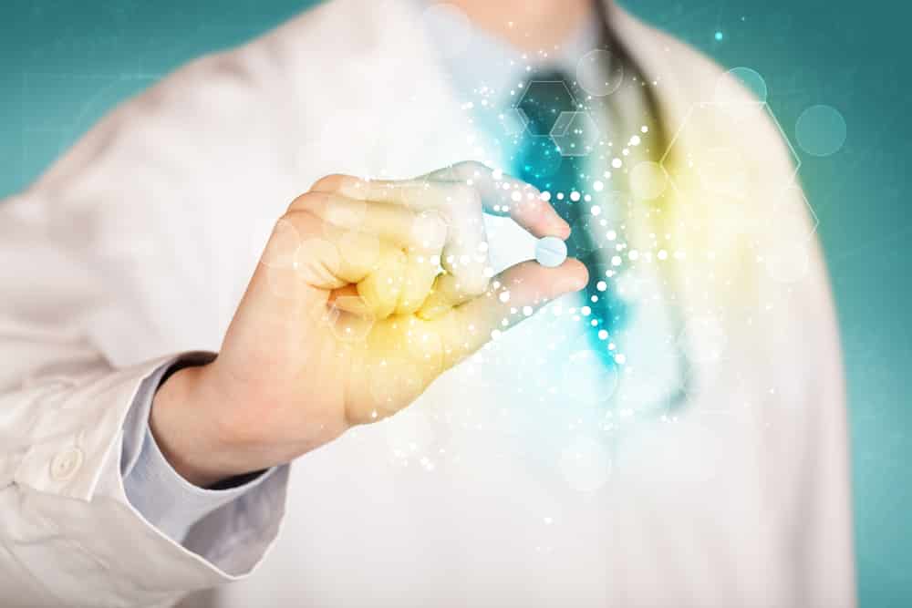 A male doctor in white coat with a stethoscope holding a pill with glowing colorful dots and lines