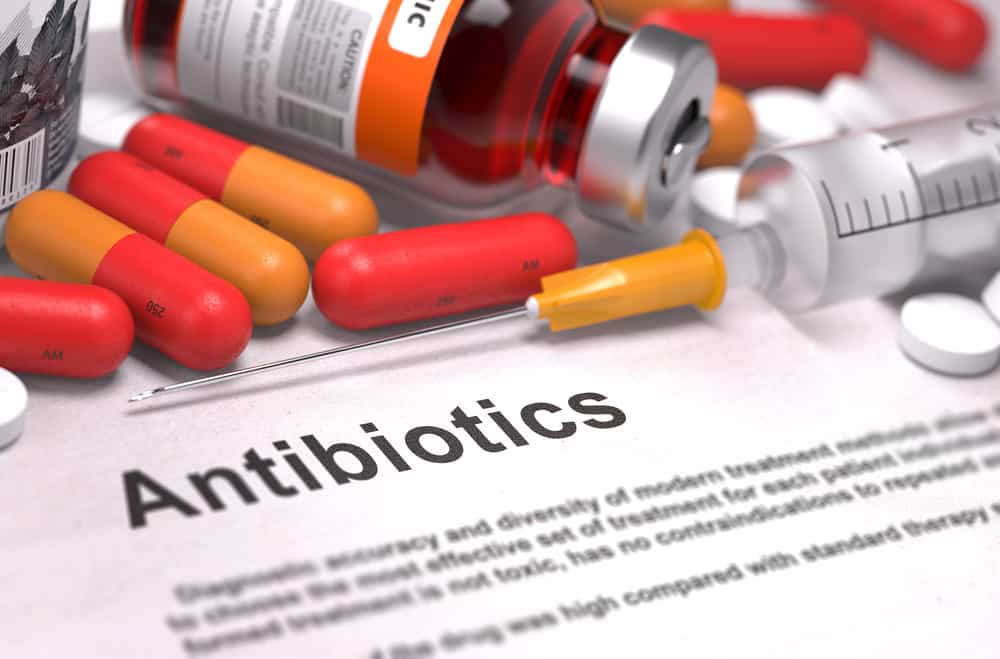 Antibiotics - Printed Diagnosis with Blurred Text. On Background of Medicaments Composition - Red Pills, Injections and Syringe.