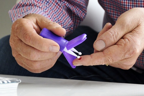 Patient using a Mitra device to collect a blood microsample at home