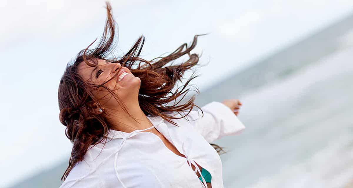 Woman enjoying the windy weather at the beach and feeling content after taking a wellness test