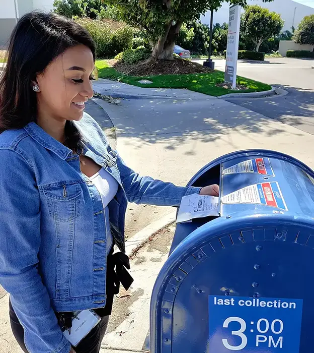 A young women places an envelope carrying dried micro samples in a large street mail box