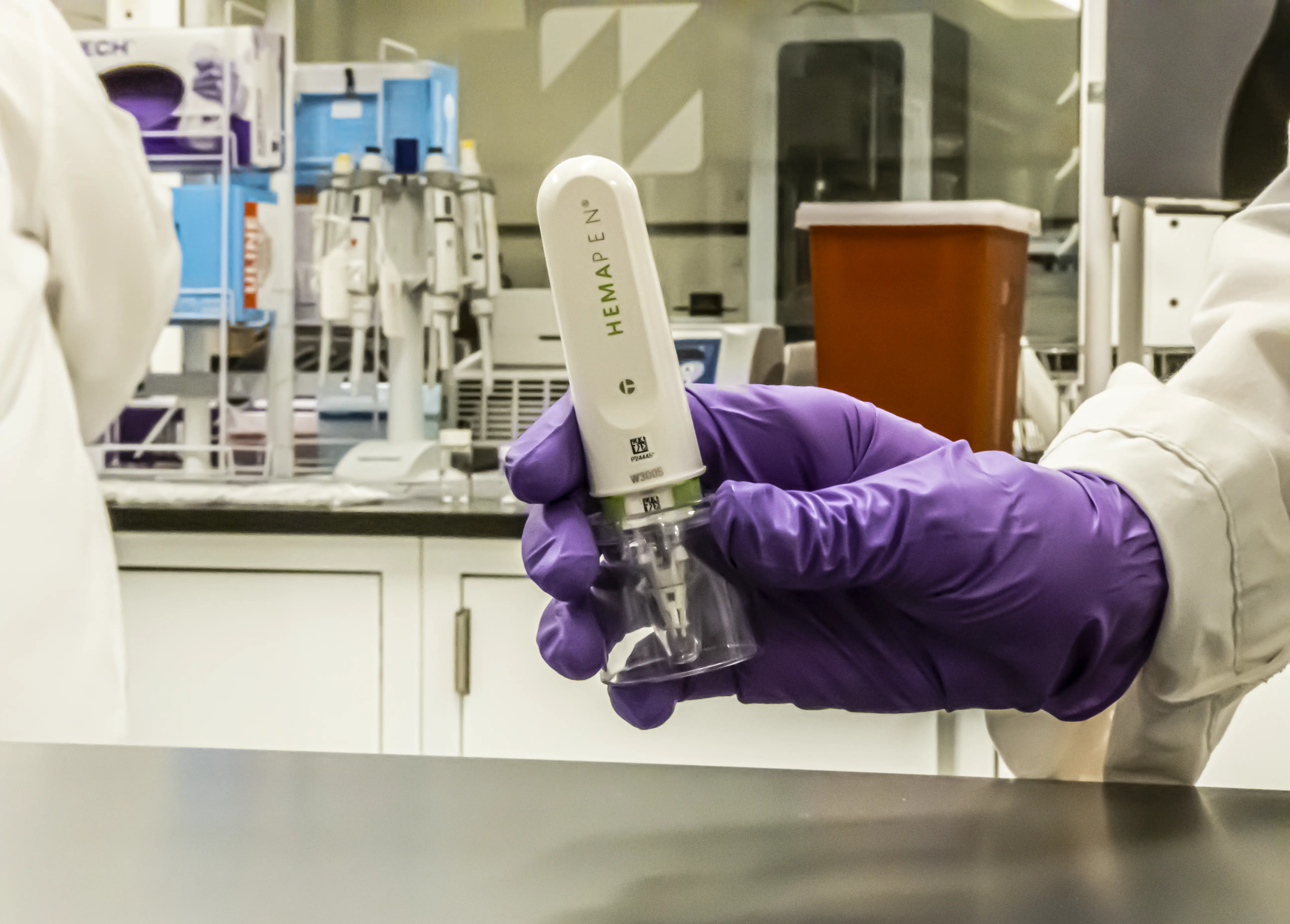 A gloved hand in a laboratory hold a hemapen device